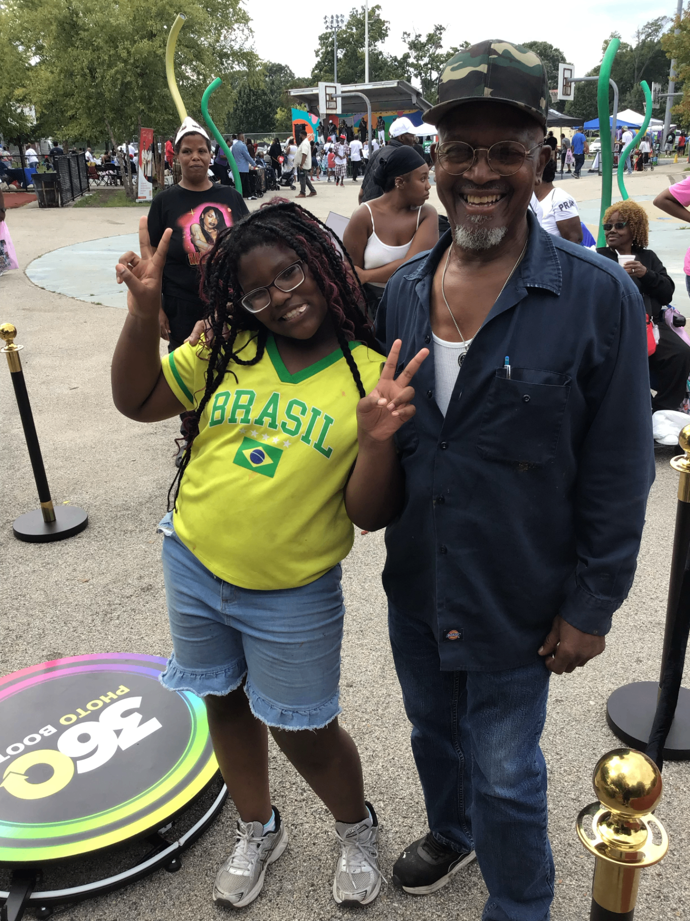 Guests posing beside the 360 photo booth at an outdoor event
